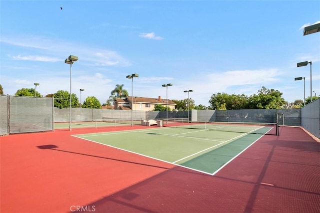 view of tennis court with community basketball court and fence