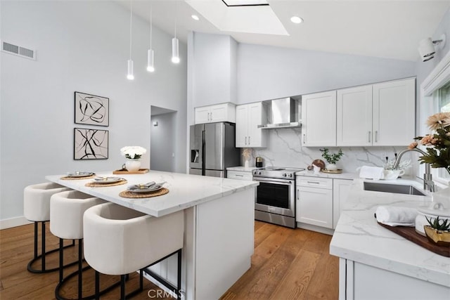 8 Recodo, Irvine, CA 92620 - kitchen featuring stainless steel appliances, wall chimney exhaust hood, a sink, a skylight, and high vaulted ceiling