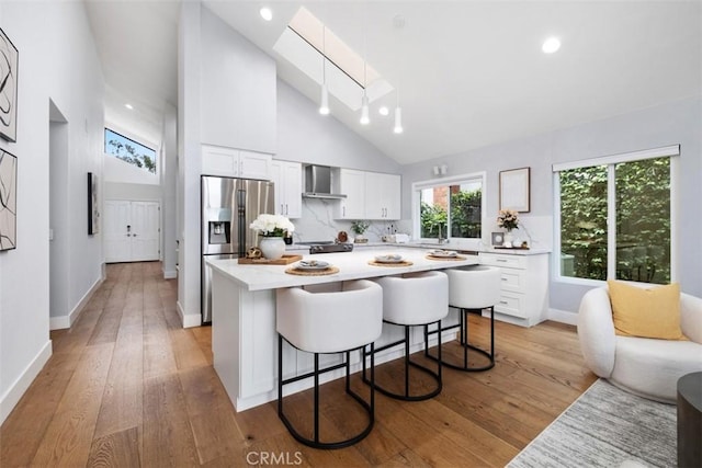 8 Recodo, Irvine, CA 92620 - kitchen featuring wall chimney range hood, a skylight, stainless steel fridge with ice dispenser, light countertops, and a breakfast bar