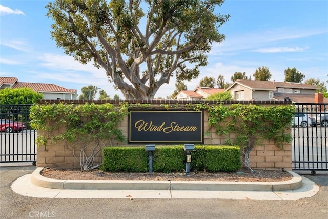 community / neighborhood sign featuring a gate and fence