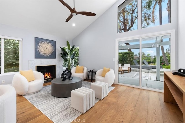 living room featuring high vaulted ceiling, a high end fireplace, wood finished floors, ceiling fan, and recessed lighting