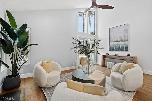 living area featuring ceiling fan, wood finished floors, and baseboards