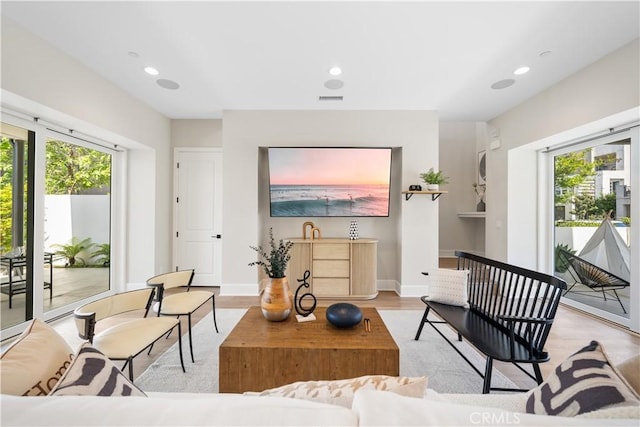 living room with recessed lighting, visible vents, plenty of natural light, and light wood-type flooring