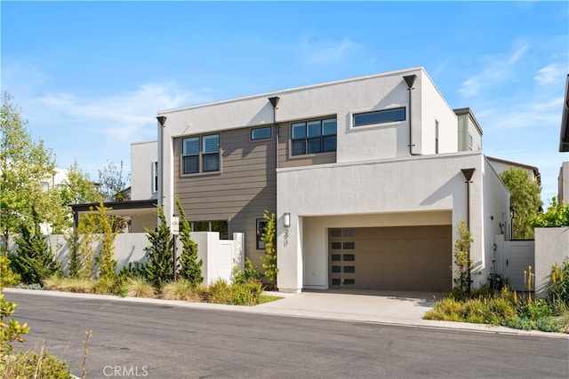 contemporary home with stucco siding, an attached garage, fence, and concrete driveway