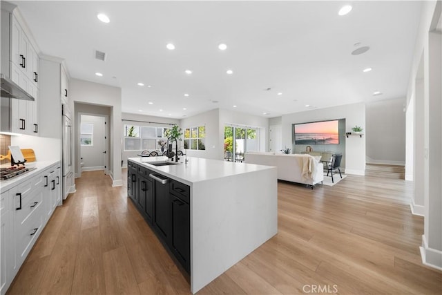 kitchen featuring a kitchen island with sink, a sink, light countertops, white cabinets, and stainless steel appliances