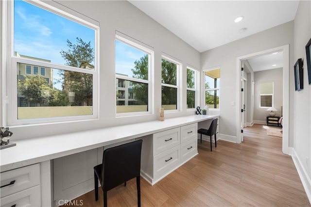 unfurnished office featuring baseboards, light wood-style flooring, recessed lighting, and built in desk