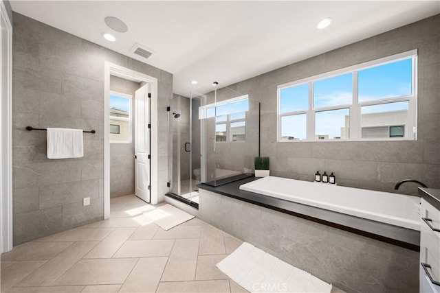 full bathroom featuring visible vents, tile walls, a bath, tile patterned floors, and a stall shower