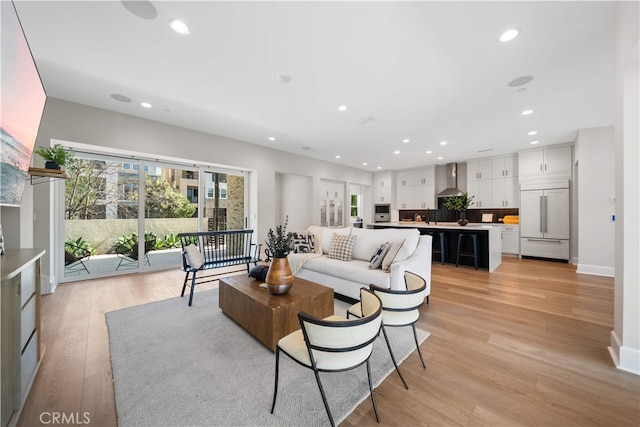 living area with recessed lighting, baseboards, and light wood-type flooring