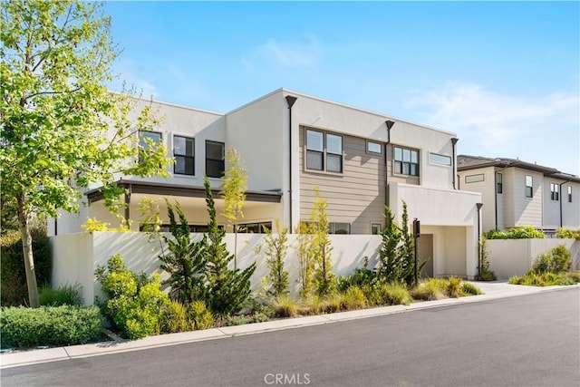 view of front of property with a garage, fence, and stucco siding