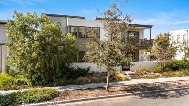 contemporary home with stucco siding and a balcony