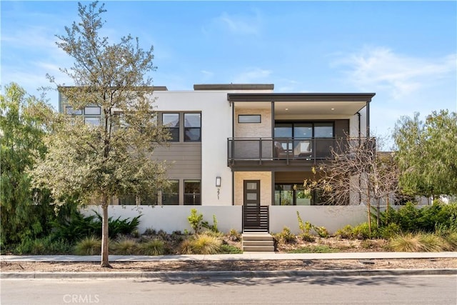 view of front of house with fence private yard, a balcony, and stucco siding