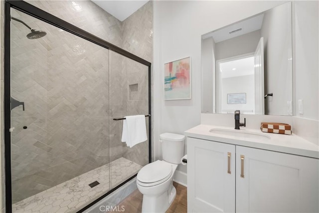 full bathroom featuring vanity, visible vents, wood finished floors, toilet, and a shower stall