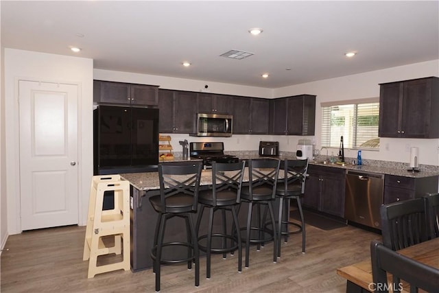 1322 Division Ct, Hemet, CA 92543 - kitchen with appliances with stainless steel finishes, light wood-type flooring, a breakfast bar area, dark brown cabinetry, and recessed lighting