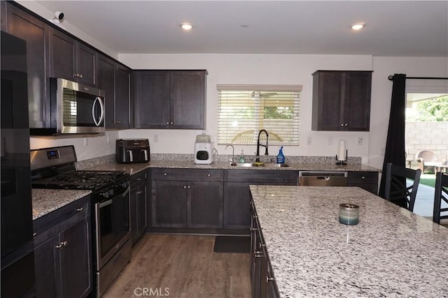 1322 Division Ct, Hemet, CA 92543 - kitchen featuring stainless steel appliances, wood finished floors, light stone countertops, dark brown cabinets, and recessed lighting