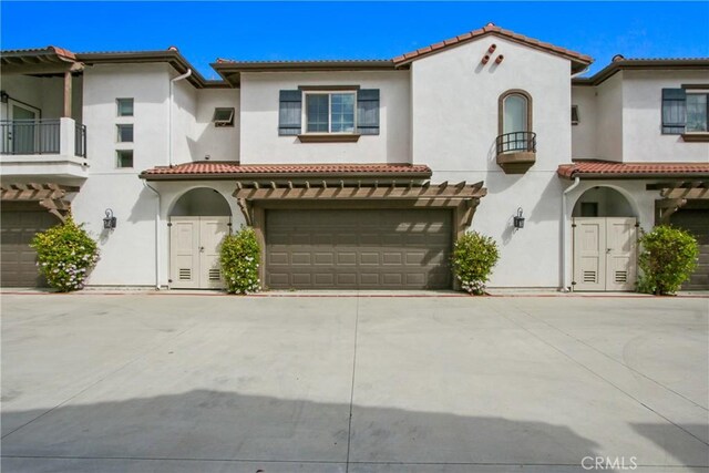 mediterranean / spanish-style home with a tile roof, a balcony, and stucco siding