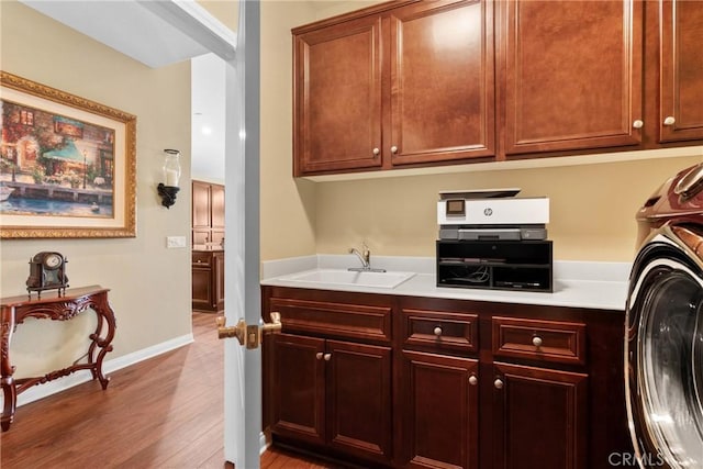 washroom with laundry area, a sink, washer / clothes dryer, baseboards, and wood finished floors