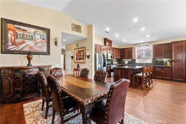 dining area with visible vents, light wood-style flooring, and lofted ceiling