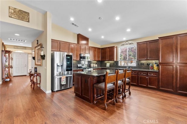 kitchen with visible vents, a center island, dark countertops, and stainless steel appliances