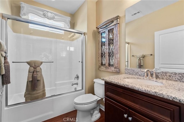 full bathroom featuring visible vents, wood finished floors, vanity, toilet, and shower / bath combination with glass door