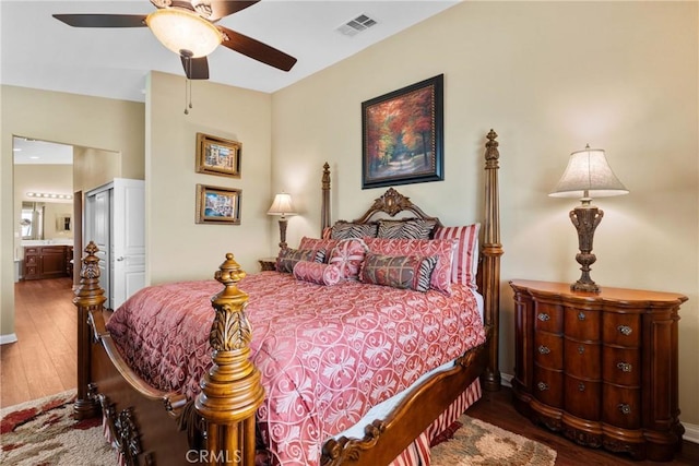 bedroom with ensuite bathroom, a ceiling fan, wood finished floors, and visible vents