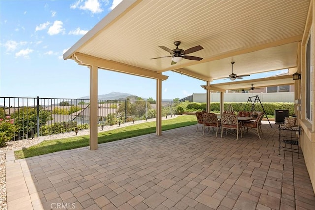 view of patio with ceiling fan, a mountain view, outdoor dining area, and a fenced backyard