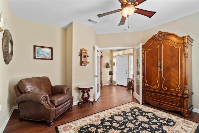 sitting room with baseboards, a ceiling fan, wood finished floors, and visible vents