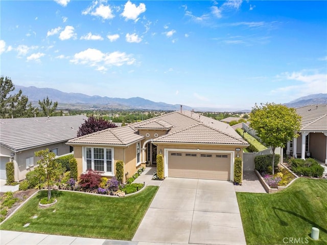ranch-style home with a tile roof, a garage, stucco siding, a mountain view, and driveway