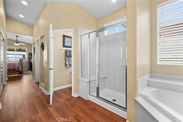 ensuite bathroom featuring wood finished floors, a ceiling fan, a stall shower, and a wealth of natural light