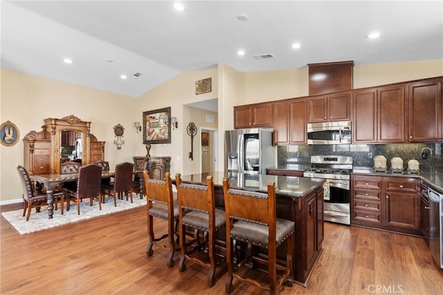 kitchen featuring a breakfast bar area, a kitchen island, visible vents, appliances with stainless steel finishes, and wood finished floors