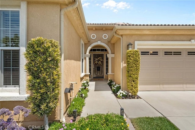entrance to property with concrete driveway, stucco siding, and an attached garage