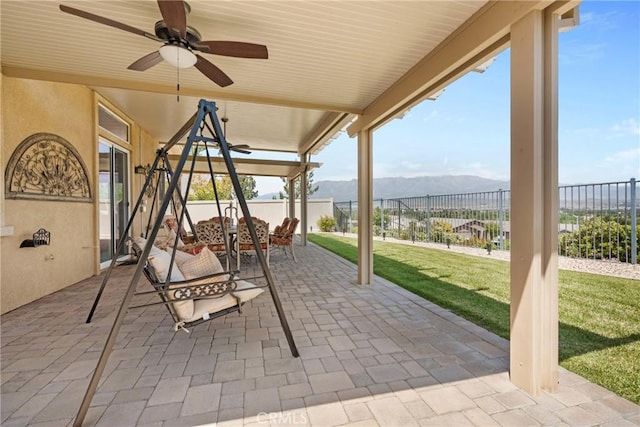 view of patio / terrace featuring outdoor dining area, a fenced backyard, ceiling fan, and a mountain view
