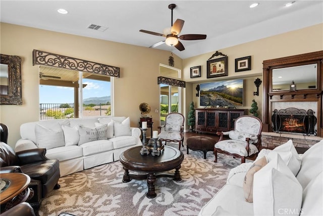 living room featuring visible vents, a ceiling fan, a warm lit fireplace, and recessed lighting