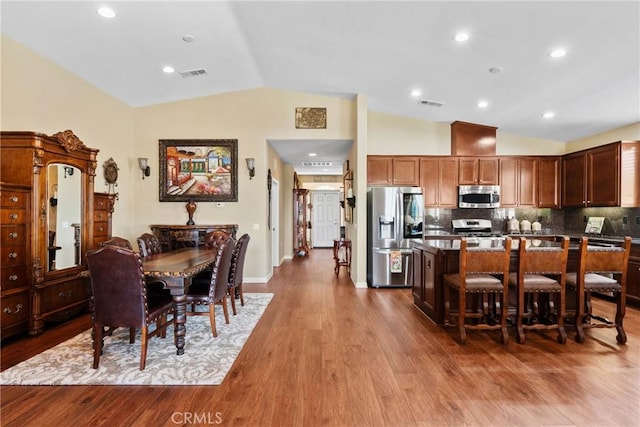 dining room featuring visible vents, baseboards, lofted ceiling, and wood finished floors