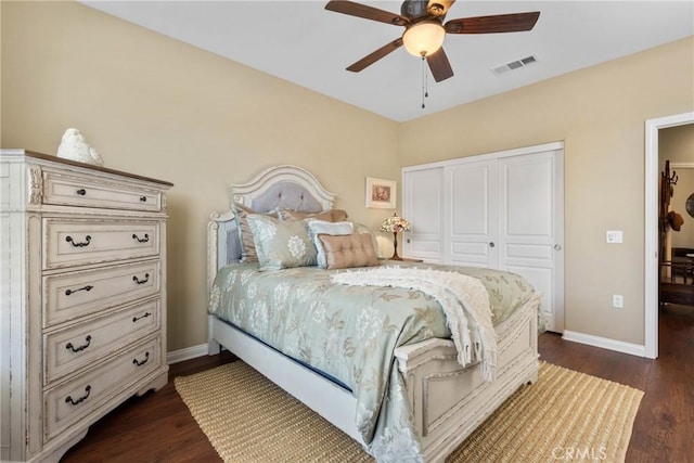 bedroom with ceiling fan, visible vents, dark wood finished floors, baseboards, and a closet