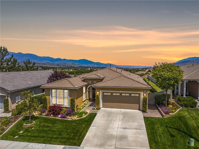 view of front facade featuring a mountain view, an attached garage, driveway, and a front yard