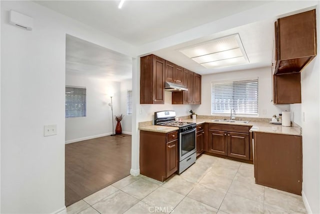 542 W Grand Ave, Pomona, CA 91766 - kitchen featuring light tile patterned flooring, baseboards, under cabinet range hood, a sink, and gas stove