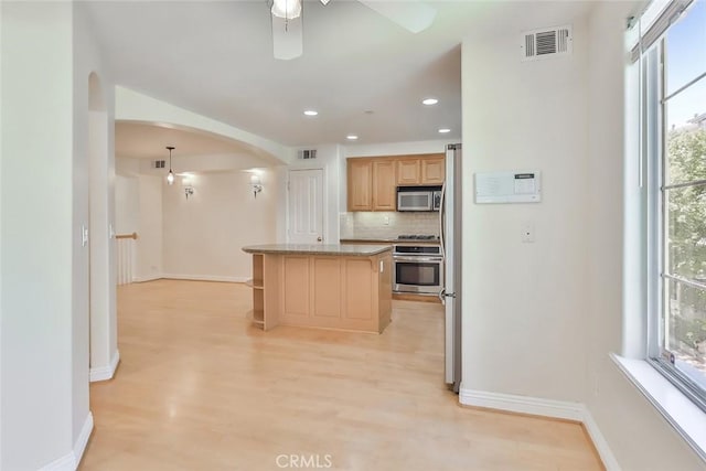 kitchen with ceiling fan, visible vents, appliances with stainless steel finishes, arched walkways, and baseboards