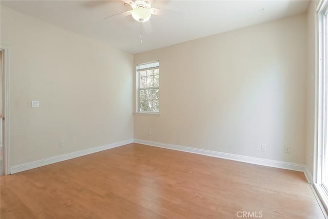 empty room featuring ceiling fan, baseboards, and light wood-type flooring
