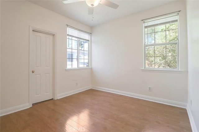 spare room with plenty of natural light, a ceiling fan, baseboards, and wood finished floors