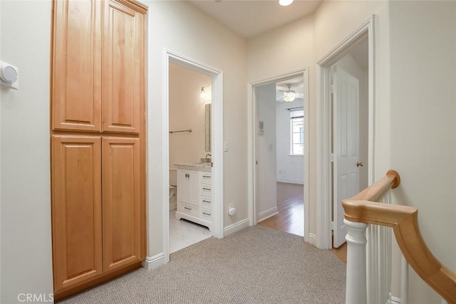 hallway featuring baseboards, light carpet, and an upstairs landing