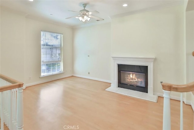 unfurnished living room featuring a glass covered fireplace, wood finished floors, baseboards, ceiling fan, and recessed lighting