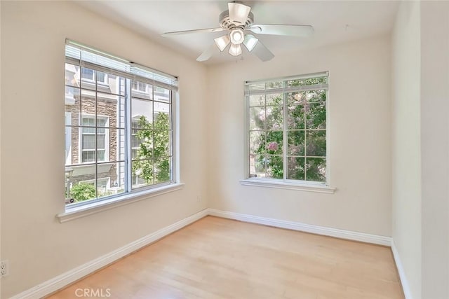 unfurnished room featuring baseboards, a healthy amount of sunlight, and wood finished floors