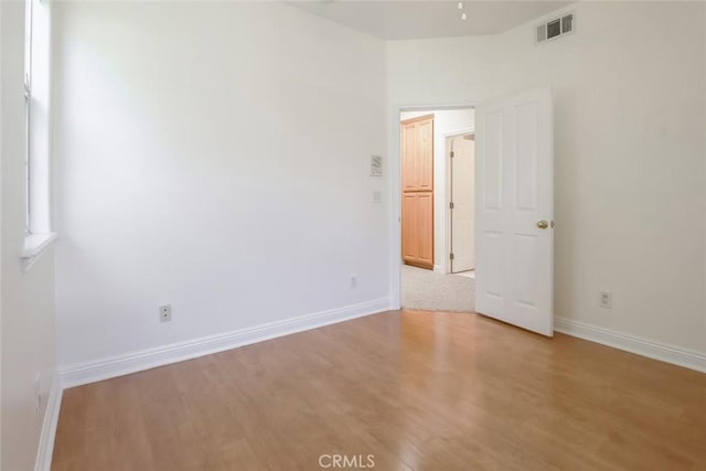 unfurnished room with baseboards, visible vents, and light wood finished floors