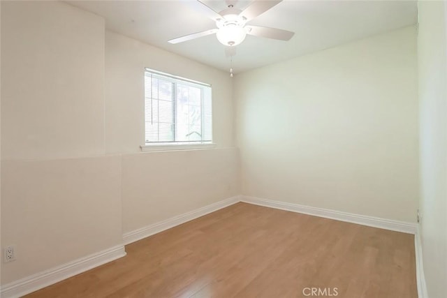 spare room featuring a ceiling fan, baseboards, and light wood-style flooring