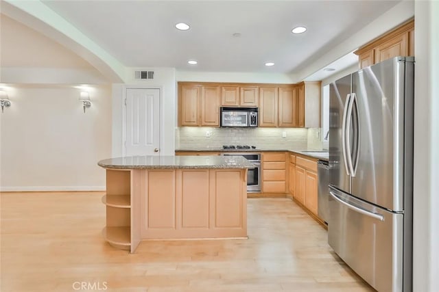 kitchen featuring visible vents, decorative backsplash, a kitchen island, light stone counters, and stainless steel appliances