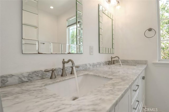full bathroom with double vanity, a wealth of natural light, and a sink