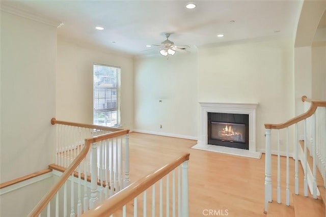 interior space featuring ceiling fan, crown molding, wood finished floors, a glass covered fireplace, and recessed lighting