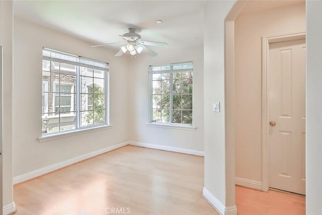 spare room with arched walkways, baseboards, wood finished floors, and a wealth of natural light
