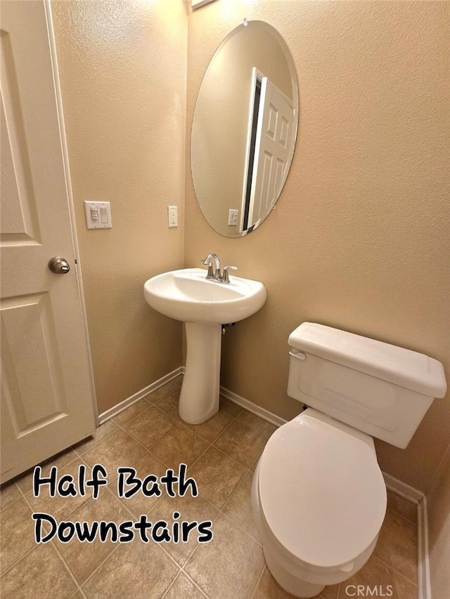 bathroom featuring toilet, baseboards, and tile patterned flooring