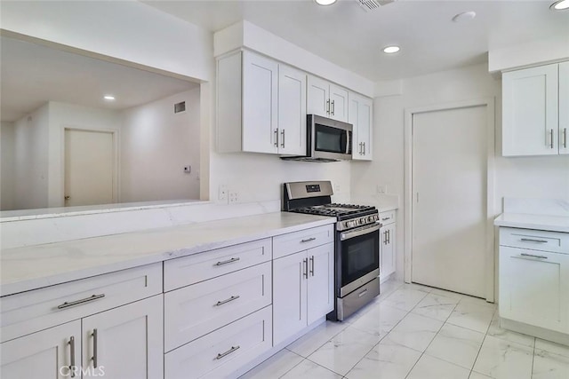 kitchen with white cabinets, recessed lighting, appliances with stainless steel finishes, and marble finish floor